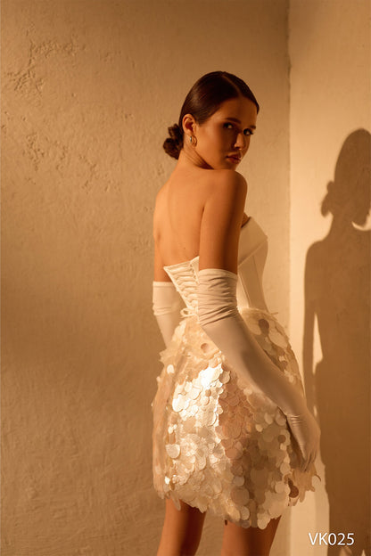 Back view of ivory strapless bridal mini dress with lace-up corset and reflective disc skirt, style VK025